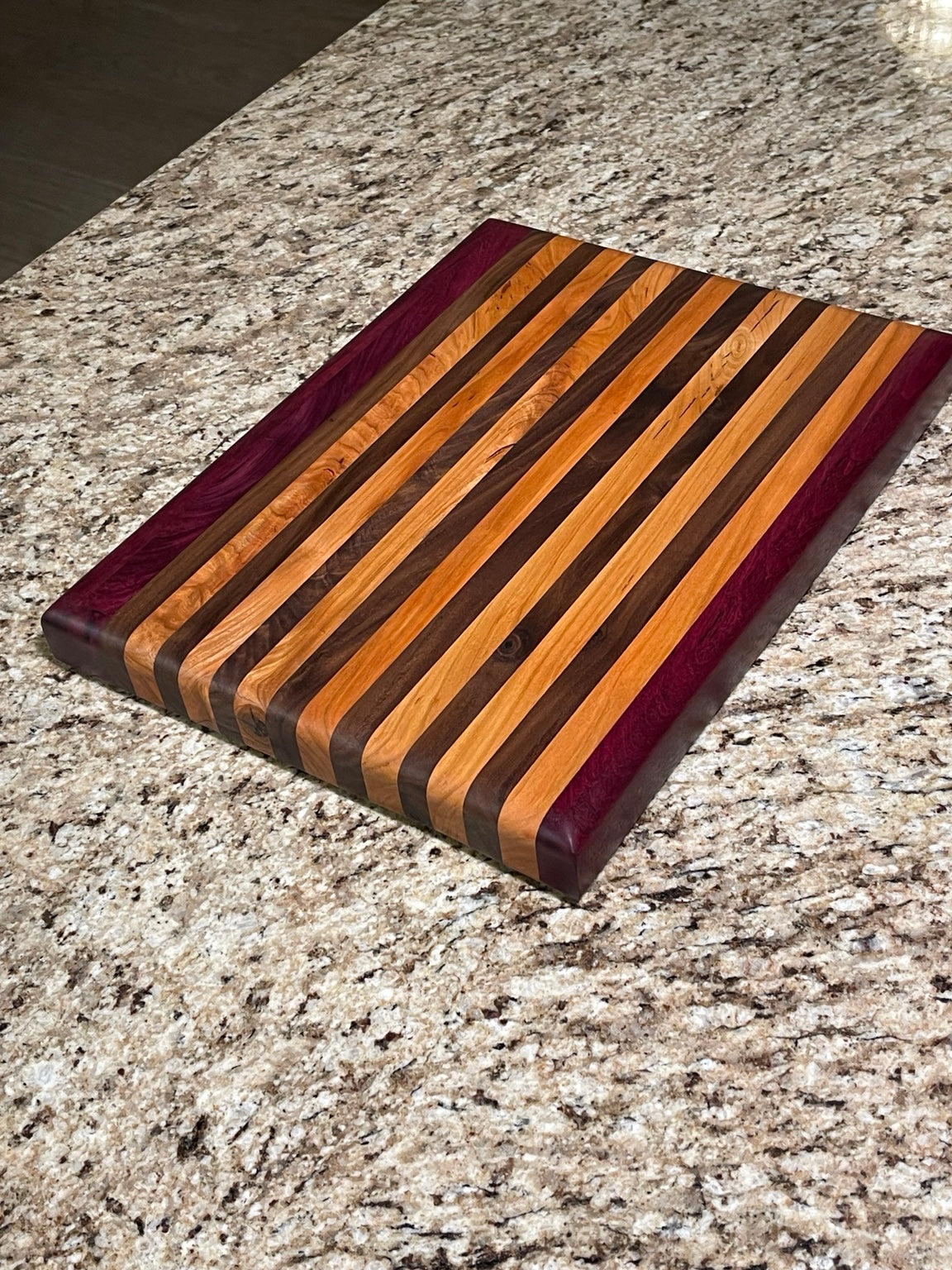 Handcrafted side grain cutting board with mixed hardwoods and Purpleheart accents
