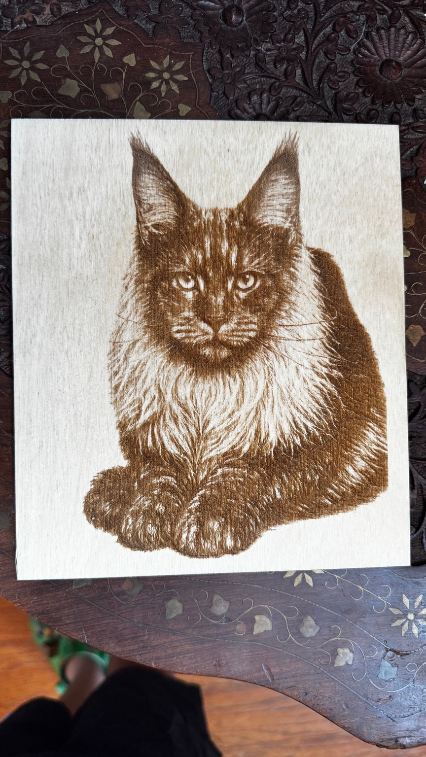 Handheld square wood engraving of a Maine Coon cat portrait